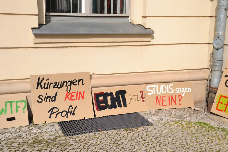 Protestbilder lehnen an einer Hauswand.