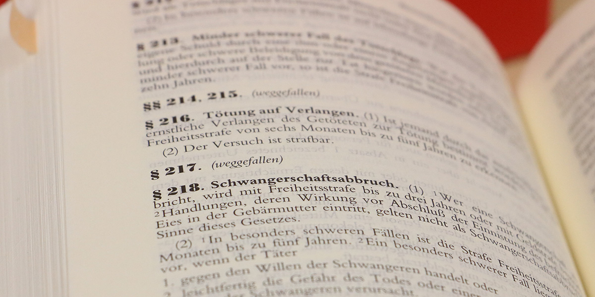 KI generiert: Das Bild zeigt eine Buchseite aus einem deutschen Gesetzbuch mit Paragraphen, die sich auf strafrechtliche Bestimmungen beziehen. Besonders hervorgehoben sind die Paragraphen 216 und 218, die sich mit Tötung auf Verlangen und Schwangerschaftsabbruch befassen.
