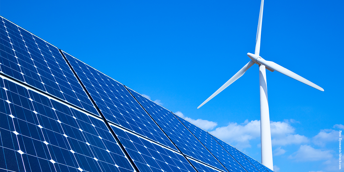 KI generiert: Das Bild zeigt Solarpaneele im Vordergrund und ein Windrad im Hintergrund vor einem klaren blauen Himmel. Der Hauptinhalt des Bildes liegt in der Darstellung erneuerbarer Energien.