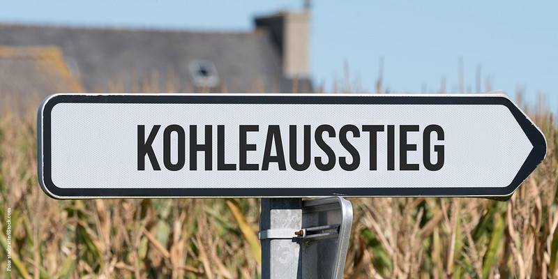 KI generiert: Das Bild zeigt ein Straßenschild mit der Aufschrift "Kohleausstieg", das auf die Wende hin zu erneuerbaren Energien hinweist. Im Hintergrund sind Natur und Gebäude zu sehen.