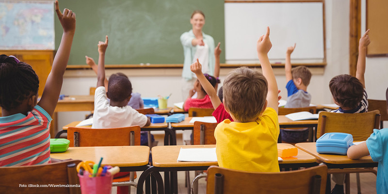 Schüler*innen sitzen im Unterricht und melden sich. 