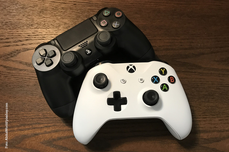 KI generiert: Das Bild zeigt zwei Gaming-Controller, einen schwarzen und einen weißen, auf einem Holztisch. Der schwarze Controller gehört zu einer PlayStation-Konsole, während der weiße zu einer Xbox-Konsole gehört.