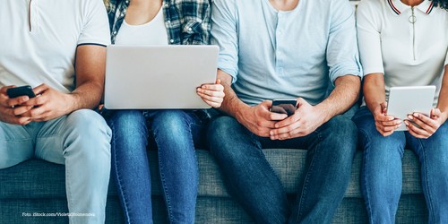 KI generiert: Das Bild zeigt vier Personen, die auf einer Couch sitzen und jeweils ein elektronisches Gerät wie Smartphone, Laptop oder Tablet in den Händen halten. Es illustriert die Nutzung von moderner Technologie im Alltag.